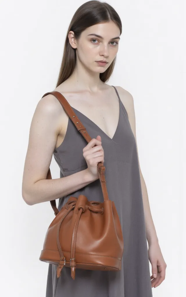 A French female model with a Drawstring bag, wearing a dress, against a white background, in a front   facing close   up